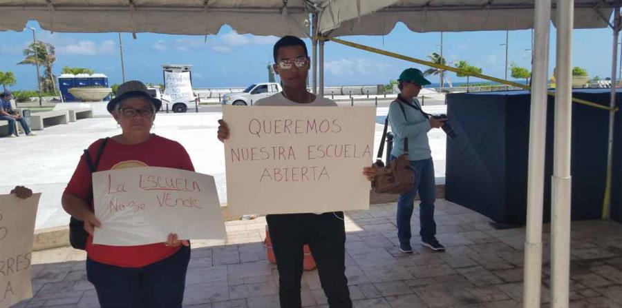 Dos manifestantes muestran sus pancartas durante la protesta. (horizontal-x3)