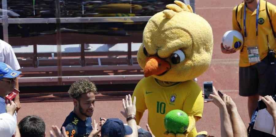 En esta foto del 12 de junio de 2018, Canarinho, la mascota de Brasil, sostiene un balón junto a Neymar, al final de un entrenamiento en Sochi, Rusia (horizontal-x3)