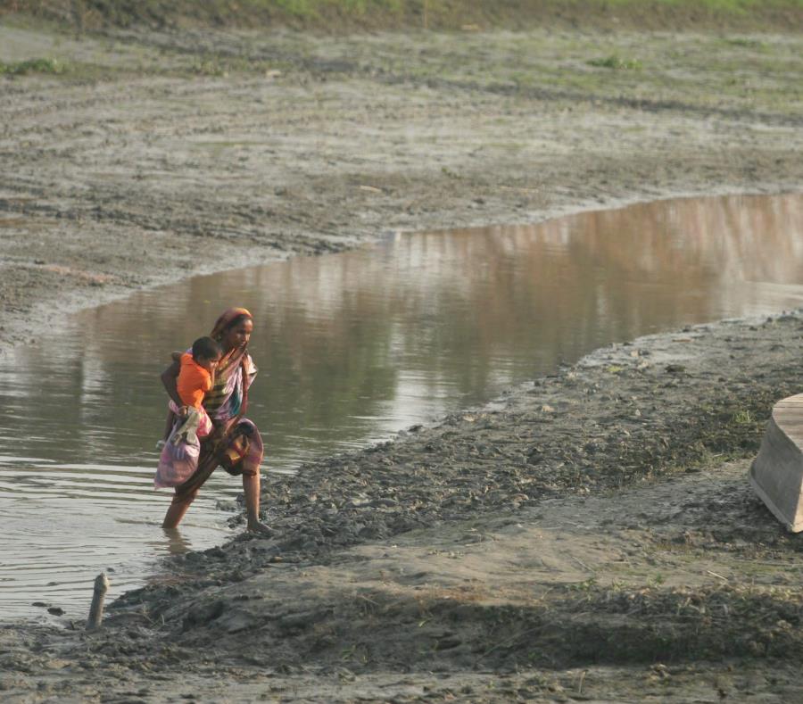 Una mujer camina por un canal casi seco con su hijo en brazos en la ciudad de Savar, Bangladesh (semisquare-x3)