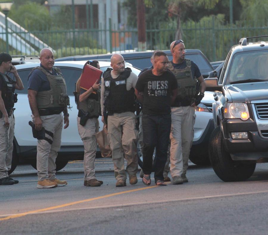 Dos agentes del Servicio de Inmigración y Control de Aduanas (ICE-HSI, por sus siglas en inglés) trasladan a un hombre arrestado. (GFR Media) (semisquare-x3)