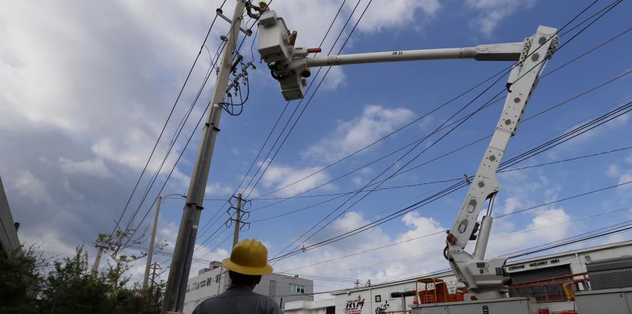 Dos empleados de la AEE reparan la electricidad en Santurce. (EFE) (horizontal-x3)