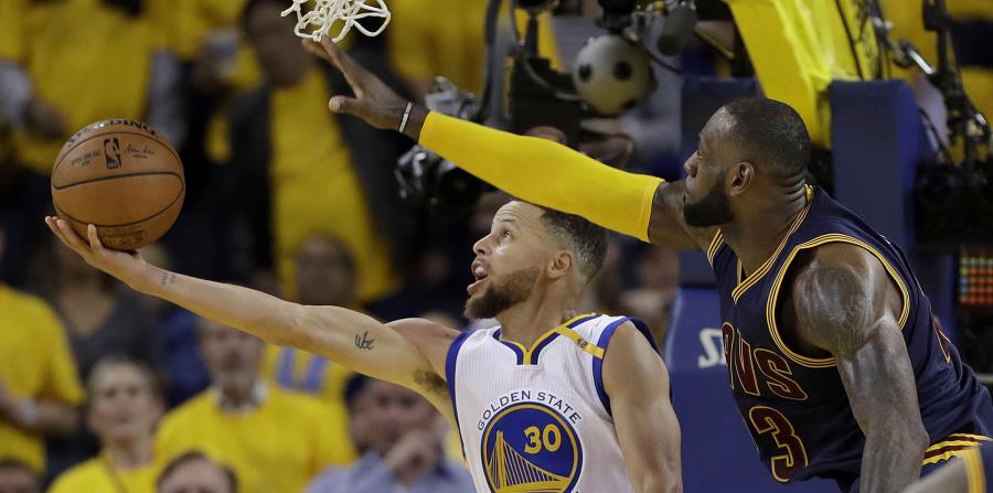 El líder de los Cavaliers, LeBron James, intenta quitarle el balón a Stephen Curry, de los Warriors. (AP) (horizontal-x3)