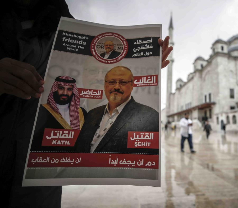 Un hombre sostiene un cartel que muestra imágenes del príncipe heredero saudí Muhammed bin Salman y del periodista Jamal Khashoggi, en el que se describe al príncipe como