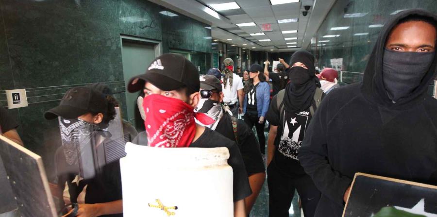 Manifestantes cargan pancartas y cantan consignas en el vestíbulo del edificio. (horizontal-x3)