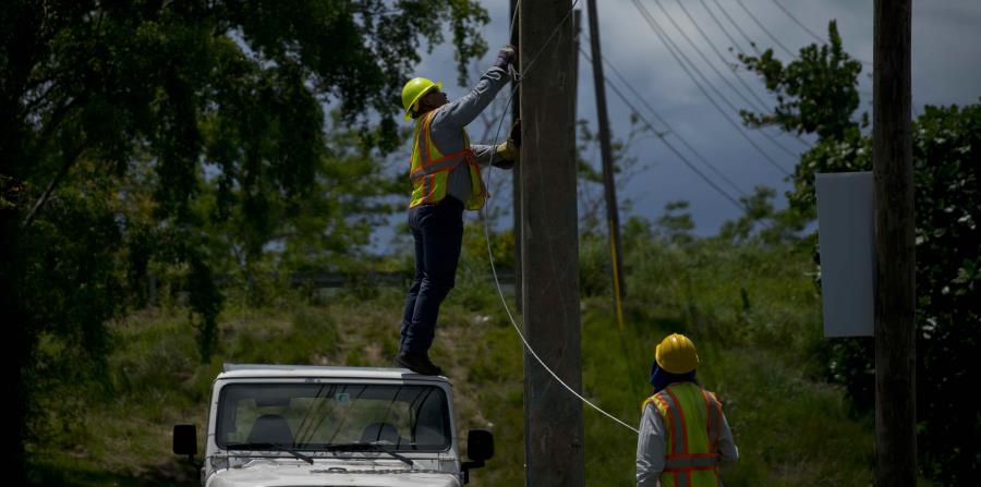 Trabajadores de la brigada de reparaciones eléctricas retiran viejos cables de un poste en San Germán. (AP) (horizontal-x3)