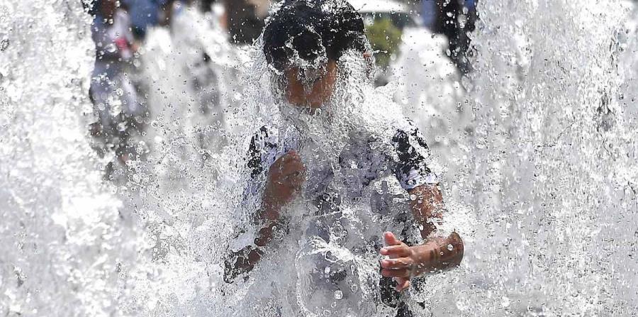 Un niño se refresca en una fuente. (EFE) (horizontal-x3)