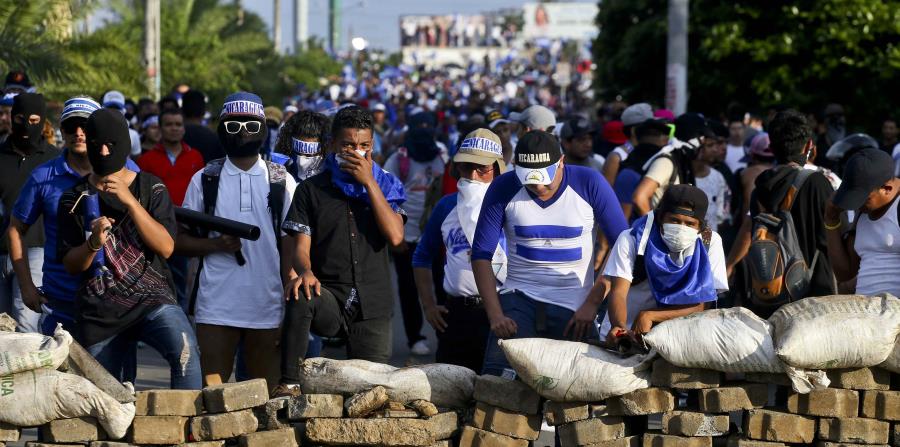 Manifestantes antigubernamentales se ponen a cubierto detrás de una barricada tras enfrentamientos durante una marcha contra el gobierno de Daniel Ortega, en Managua, Nicaragua. (AP) (horizontal-x3)
