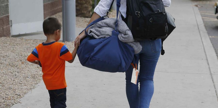 José Jr., de 3 años y natural de Honduras, recibe ayuda de una trabajadora del Southern Poverty Law Center antes de reunirse con su padre, el 10 de julio de 2018, en Phoenix. (AP (horizontal-x3)