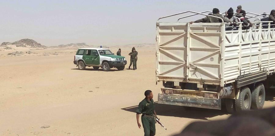 gendarmes argelinos, armados con fusiles AK-47, suben a migrantes a camiones para dejarlos en la frontera con Níger. Muchos migrantes mueren después en su marcha por el desierto hacia Níger. (horizontal-x3)