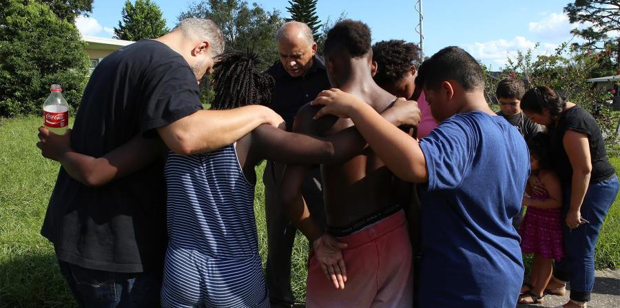 El pastor Eddie Del Valle ora con niños de la comunidad donde ocurrió la tragedia. (horizontal-x3)