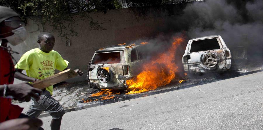 Personas corren luego que protestantes prendieron fuego a varios automóbiles durante los disturbios en Haití por el alza en el precio de los combustibles. (AP / Dieu Nalio Chery) (horizontal-x3)