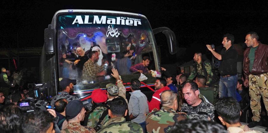 En esta imagen, distribuida por la agencia oficial de noticias siria SANA, soldados y residentes saludan a civiles tras ser liberados por el grupo Ejército del Islam, que los tenía retenidos desde 2013, en Damasco, Siria, (horizontal-x3)