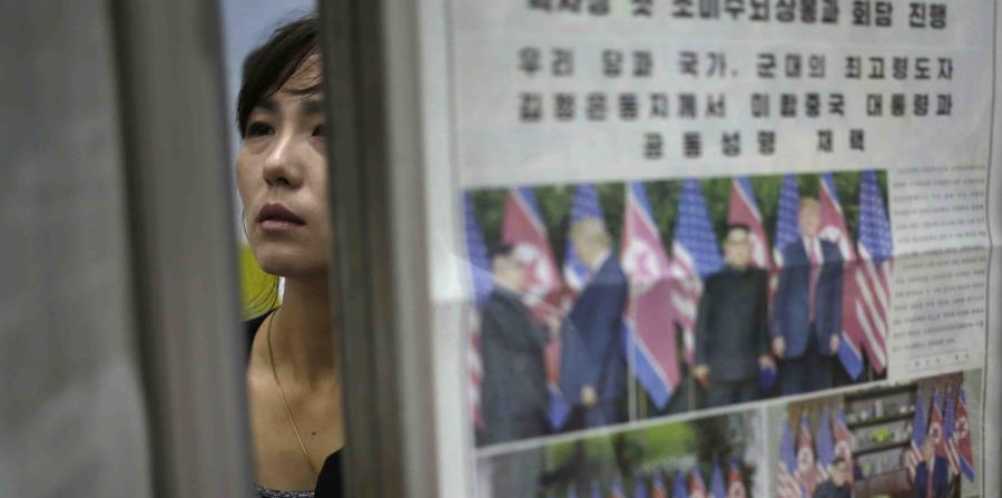Una mujer norcoreana pasa detrás de un estante de periódicos en los que se reporta la cumbre entre Donald Trump y Kim Jong-un. (AP) (horizontal-x3)