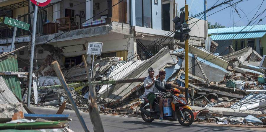 Dos hombres en una motocicleta pasan junto a construcciones arruinadas por el terremoto del domingo en Pamenang, en la isla de Lombok, Indonesia, el viernes 10 de agosto de 2018. (AP) (horizontal-x3)
