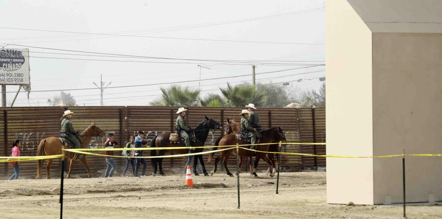 un grupo de personas detenidas por agentes a caballo de la Patrulla Fronteriza tras cruzar de forma ilegal a territorio estadounidense desde Tijuana, México, pasa junto a los prototipos de muro fronterizo, a la derecha, que se están construyendo en San Di (horizontal-x3)