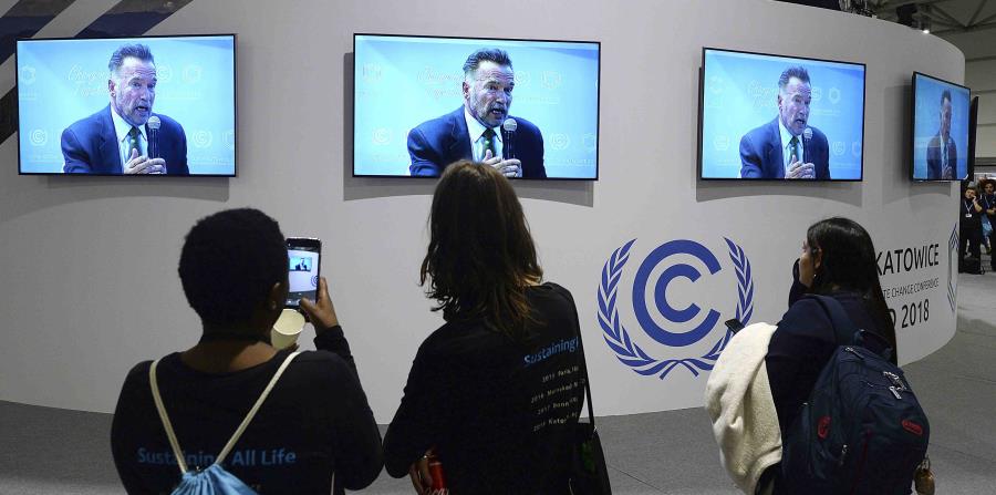 Visitantes en la Conferencia Climática de Naciones Unidas siguen el discurso de Arnold Schwarzenegger por televisión. (AP / Czarek Sokolowski) (horizontal-x3)