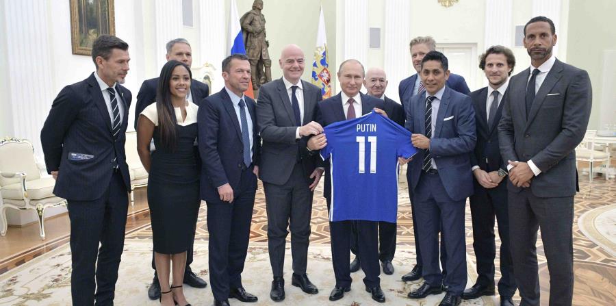 El presidente ruso Vladimir Putin sostiene una camiseta que le obsequiaron, junto al líder de la FIFA Gianni Infantino y varios exfutbolistas, al término de una reunión en el Kremlin. (AP) (horizontal-x3)