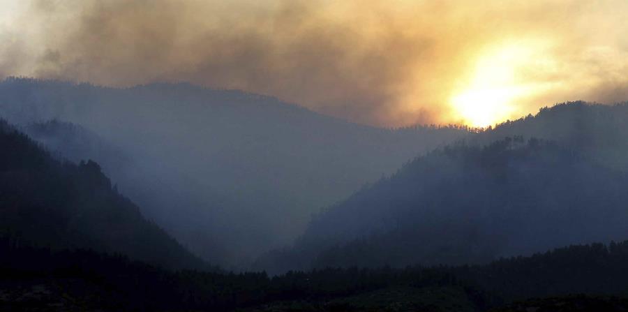 Al ponerse el sol, humo sube de un área incendiada al oeste de la subdivisión Falls Creek Ranch. (horizontal-x3)