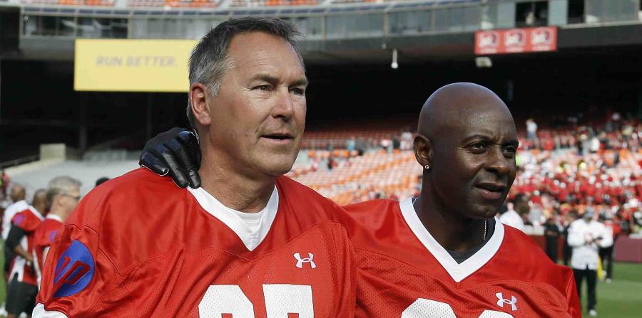 Dwight Clark, a la izquierda, camina junto a Jerry Rice por el campo de fútbol en un juego celebrado en San Francisco. (AP) (horizontal-x3)