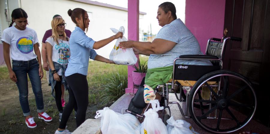 Voluntarios y personal de la organización P.E.C.E.S. le entregan suministros de primera necesidad a una vecina de la calle Del Fuego, en Punta Santiago, Humacao. (Archivo / GFR Media) (horizontal-x3)