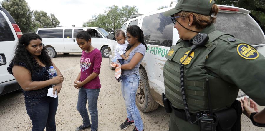 Una agente dialoga con una mujer hondureña que intentaba pasar con sus hijos. (AP) (horizontal-x3)