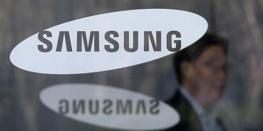 Un empleado camina detrás de un logo de la compañía Samsung. (AP) (horizontal-x3)