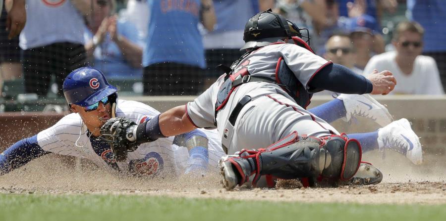 El jugador de los Cachorros de Chicago, el puertorriqueño Javier Báez, izquierda, anota al superar al receptor de los Mellizos de Minnesota, Bobby Wilson, gracias a un sencillo productor de dos carreras de Ben Zobrist durante el tercer inning del partido. (horizontal-x3)