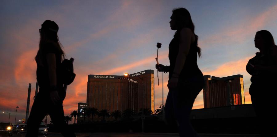 varias personas llevan flores a las inmediaciones del hotel y casino Mandalay Bay durante una vigilia por las víctimas y sobrevivientes de una balacera en Las Vegas. (AP (horizontal-x3)