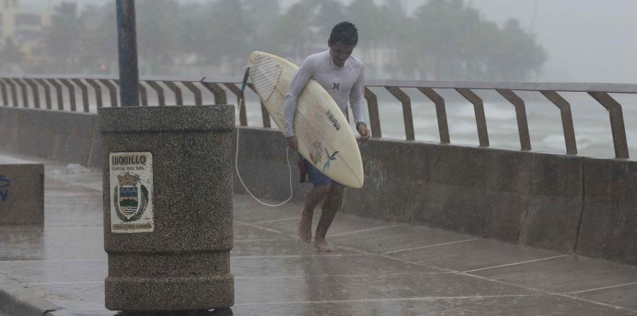Un surfer corre por una acera mientras llueve. (GFR Media) (horizontal-x3)