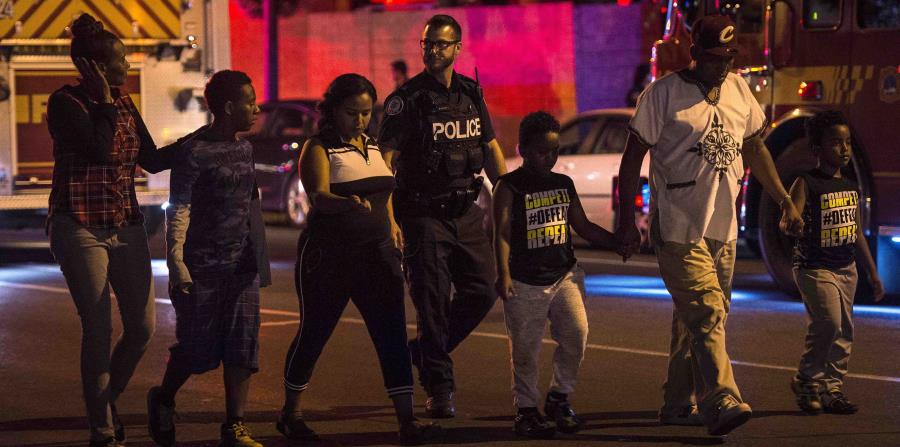 La Policía desaloja a una familia del lugar de la balacera. (AP) (horizontal-x3)