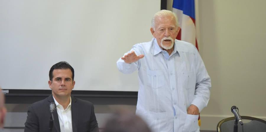 El exgobernador Carlos Romero Barceló (de pie) junto al gobernador Ricardo Rosselló durante una reunión de la Comisión de Igualdad en Miami. (horizontal-x3)