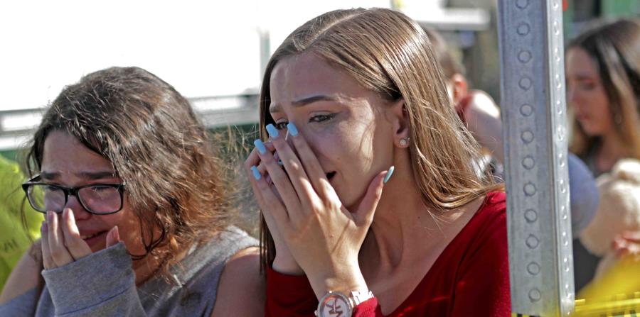 Unas estudiantes de la escuela secundaria Marjory Stoneman Douglas, en Parkland, lloran tras la masacre reportada el pasado miércoles. (AP) (horizontal-x3)