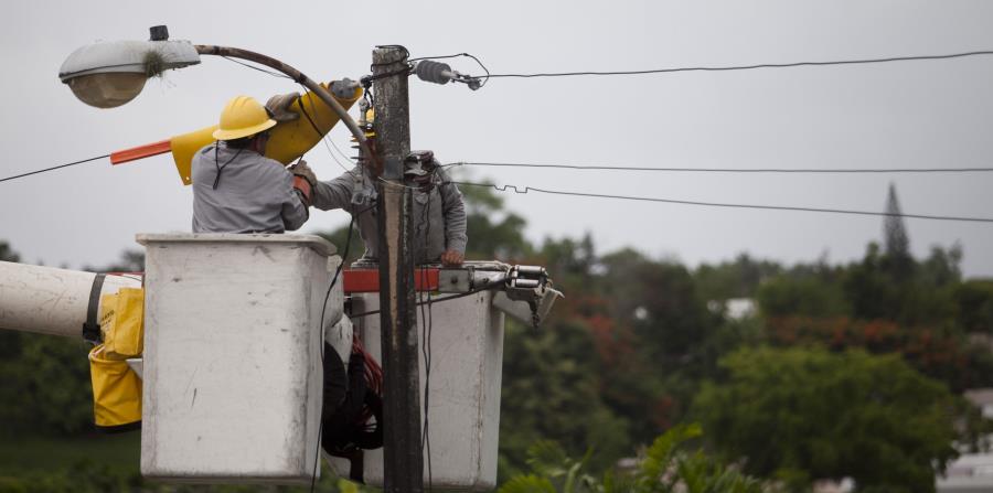 Varios trabajadores trabajan en un poste de luz. (GFR Media) (horizontal-x3)