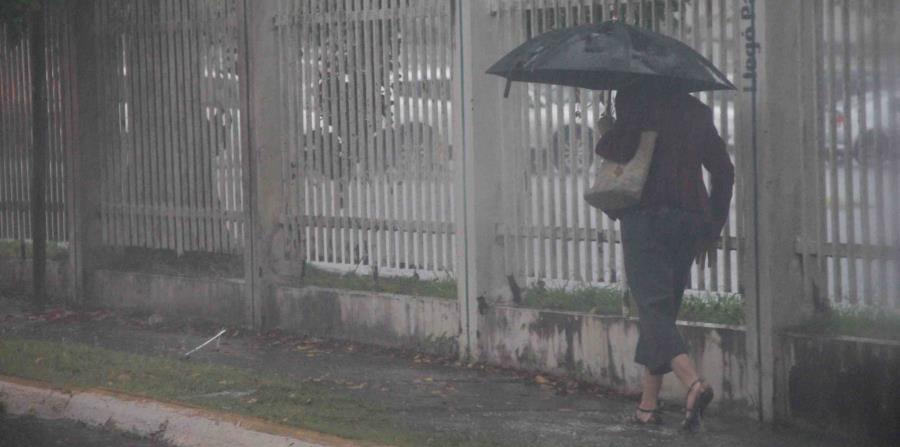 Una mujer camina por una carretera en Hato Rey con sombrilla en mano para evitar mojarse con la lluvia. (GFR Media) (horizontal-x3)