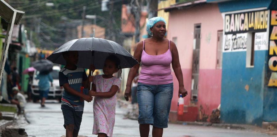 Una mujer y dos niños caminan hoy en el barrio La Ciénaga, en Santo Domingo (horizontal-x3)