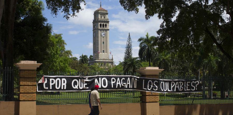 Dos estudiantes caminan frente a un letrero de protesta que fue colocado en los portones de la UPR en Río Piedras durante el proceso huelgario que impulsaron los universitarios el pasado año. (GFR Media) (horizontal-x3)