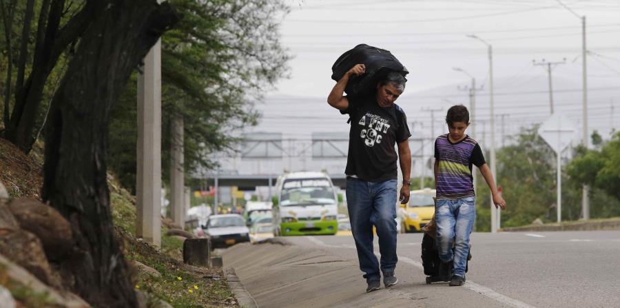 el venezolano Darwin Zapata camina acompañado por su hijo de 12 años por la carretera en Cúcuta, Colombia, mientras se dirigen a Perú. (horizontal-x3)