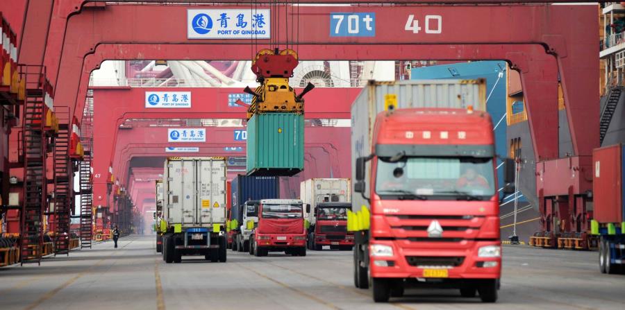 Varios camiones mientras transportan contenedores en un puerto en Qingdao, China (horizontal-x3)