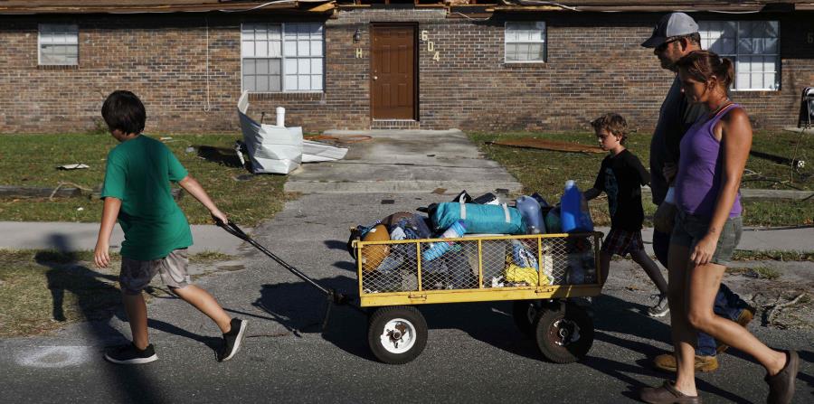 Anthony Weldon, de 11 años, tira de un carrito con las pertenencias de su familia mientras se muda junto a su hermano Thomas, de 10 años, su madre Dawn Clarke y su padre Richard Coker de su casa, que quedó inhabitable tras el paso del huracán Michael. (AP (horizontal-x3)