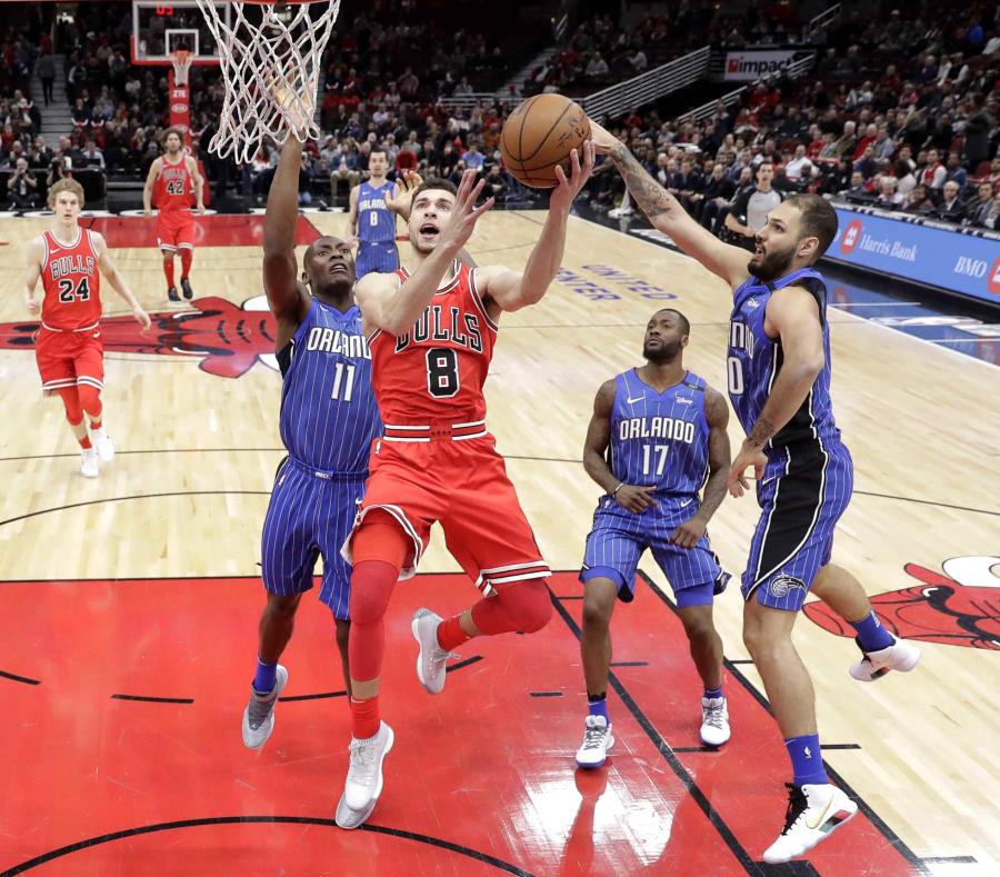 Zach LaVine, de los Bulls de Chicago, ataca el canasto entre los jugadores del Orlando Magic Bismack Biyombo (11), Evan Fournier (10) y Jonathon Simmons (17) durante la primera mitad del juego del lunes 12 de febrero de 2018 en Chicago. (AP) (semisquare-x3)