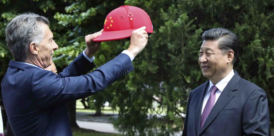 El mandatario chino Xi Jinping recibe un casco de polo decorado con la bandera de China de parte del presidente argentino Mauricio Macri. (AP) (horizontal-x3)
