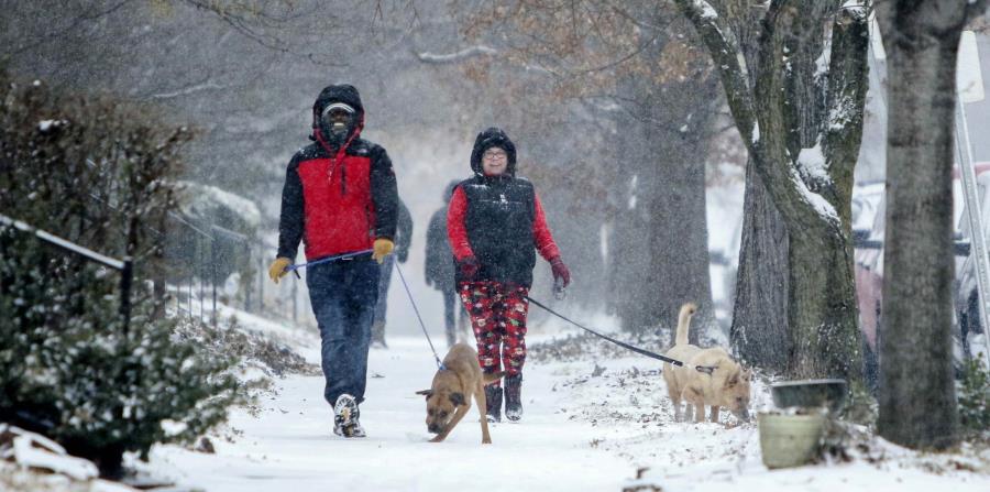 Kevin Britton y su esposa Amy Britton pasean sus perros bajo la nieve en San Luis. (AP) (horizontal-x3)