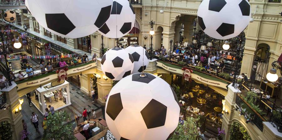 En esta imagen del viernes 29 de junio, turistas y aficionados del futbol caminan por el centro comercial GUM decorado con enormes balones de fútbol con motivo del Mundial en Moscú, Rusia. (AP) (horizontal-x3)