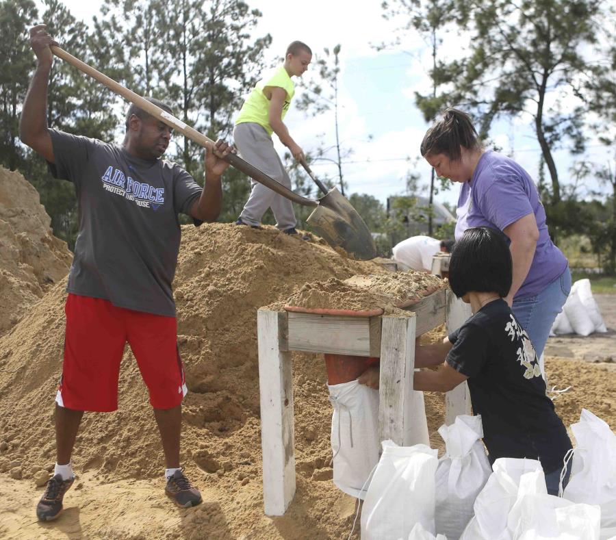 Haskel Johnson, Daniel Tippett, Jennifer Tippett y Nobuko Johnson llenan sacos de arena en Lynn Haven, Florida. (Patti Blake / News Herald vía AP) (semisquare-x3)