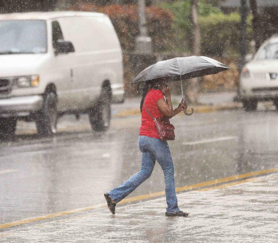 Una mujer se cubre de la lluvia con una sombrilla. (GFR Media) (semisquare-x3)
