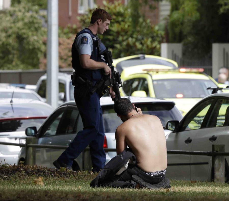 Un hombre descansa en el suelo mientras habla por su teléfono celular del otro lado de la calle de una mezquita en Christchurch, Nueva Zelanda (semisquare-x3)