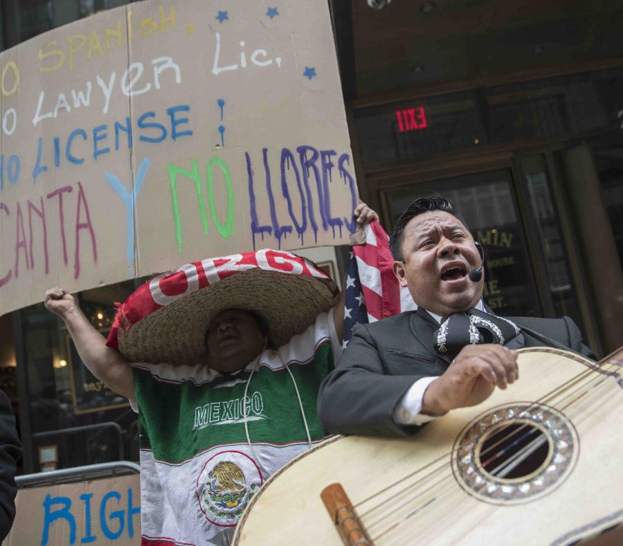 Un manifestante baila y canta con un mariachi durante una protesta al otro lado de la calle donde está el edificio que alguna vez albergó la oficina del abogado Aaron Schlossberg el viernes 18 de mayo de 2018. (AP) (semisquare-x3)