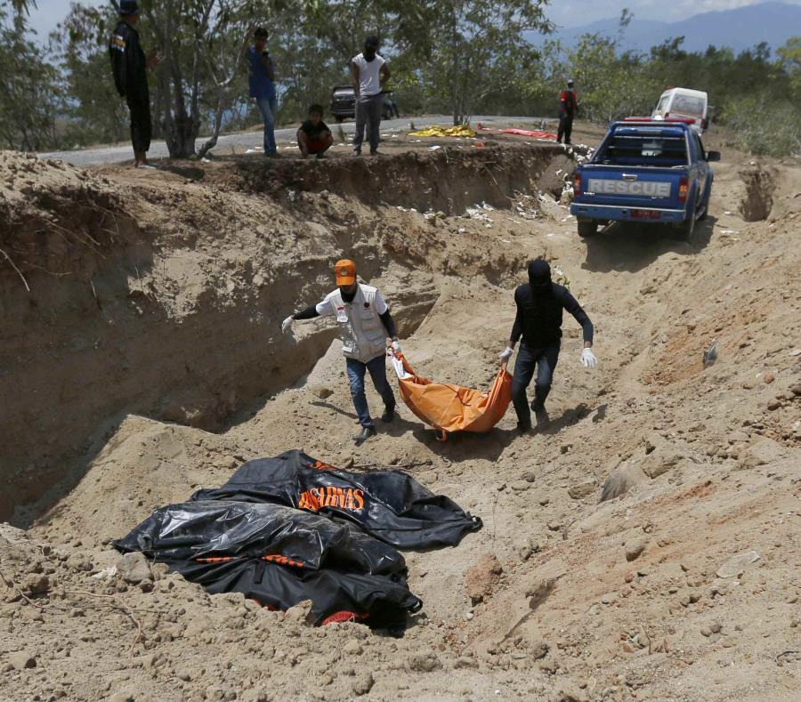 Rescatistas cargan los cadáveres para enterrarlos en una fosa común. (AP) (semisquare-x3)