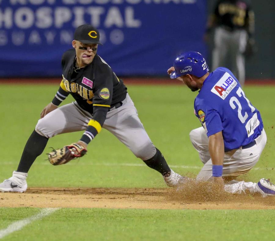 El lanzador de Carolina, Isan Diaz (a la izquierda) y intenta detener al jugador de Santurce, Raymound Fuentes, mientras llega a salvo a la segunda base. (semisquare-x3)
