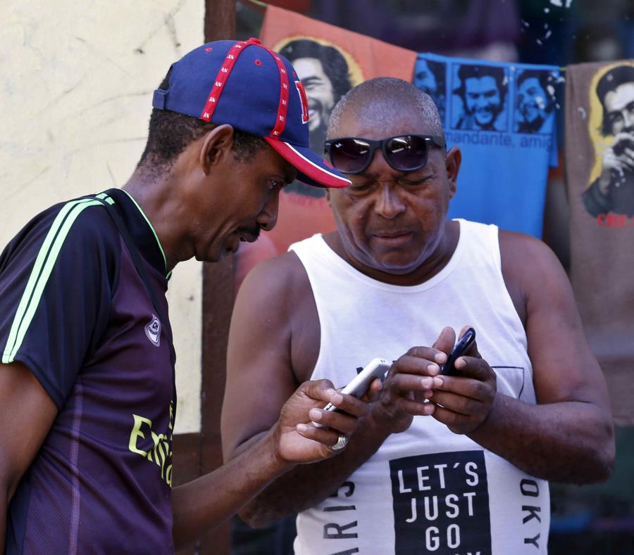 Dos clientes de Etecsa intentan conectarse al Internet mediante sus teléfonos móviles en Cuba. (EFE / Ernesto Mastrascusa) (semisquare-x3)